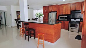 A modern kitchen with wooden cabinets, a stainless steel refrigerator, an oven, and a microwave.