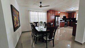 A dining area with a table and chairs, a kitchen with wooden cabinets, and a ceiling fan. - Discover this 3 bed charming country house in Llano de Perez, with AC included (Imbert)