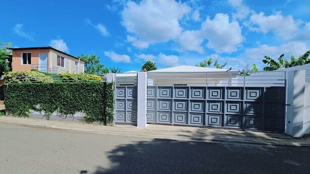 A gated property with a garage door and a building in the background. - Discover this 3 bed charming country house in Llano de Perez, with AC included (Imbert)