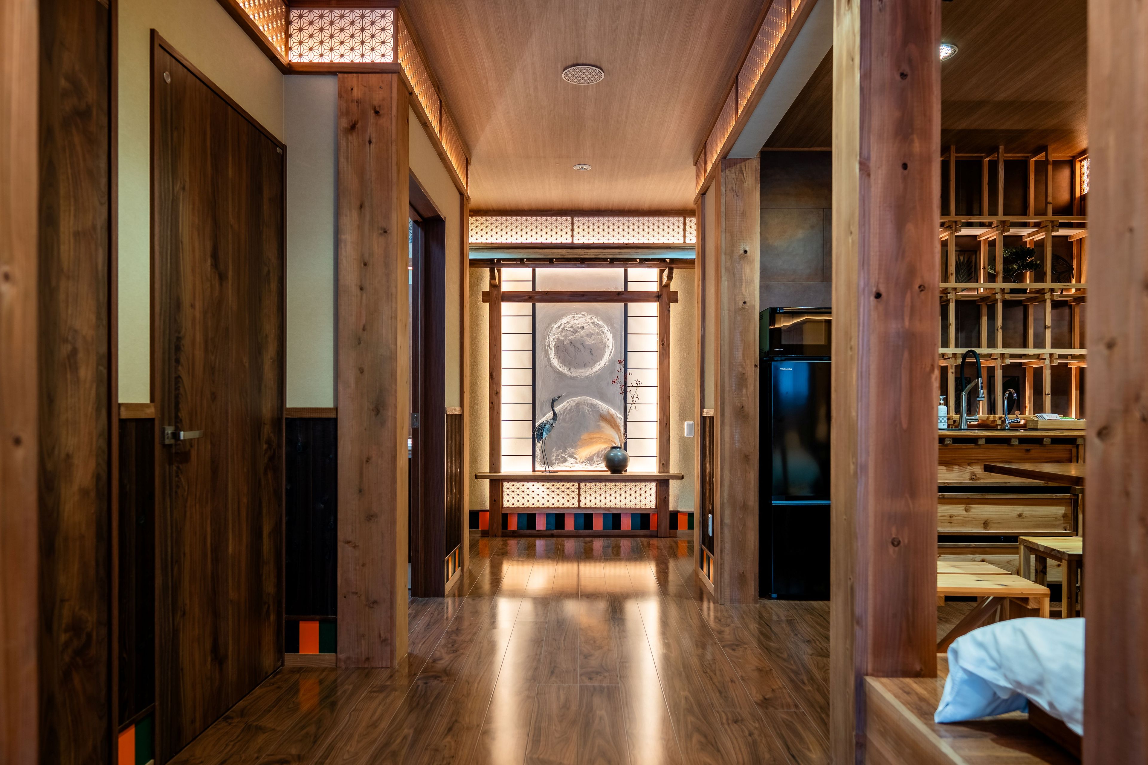 A hallway with wooden doors, a traditional Japanese sliding door, and a modern kitchen area with a refrigerator.