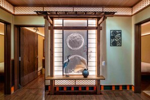 Ein Flur mit traditioneller japanischer Inneneinrichtung, darunter eine hölzerne Bank mit einer Vase und ein an der Wand befestigtes Kunstwerk.