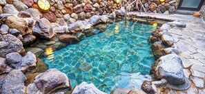 Una piscina cristalina rodeada de rocas y un muro de piedra.
