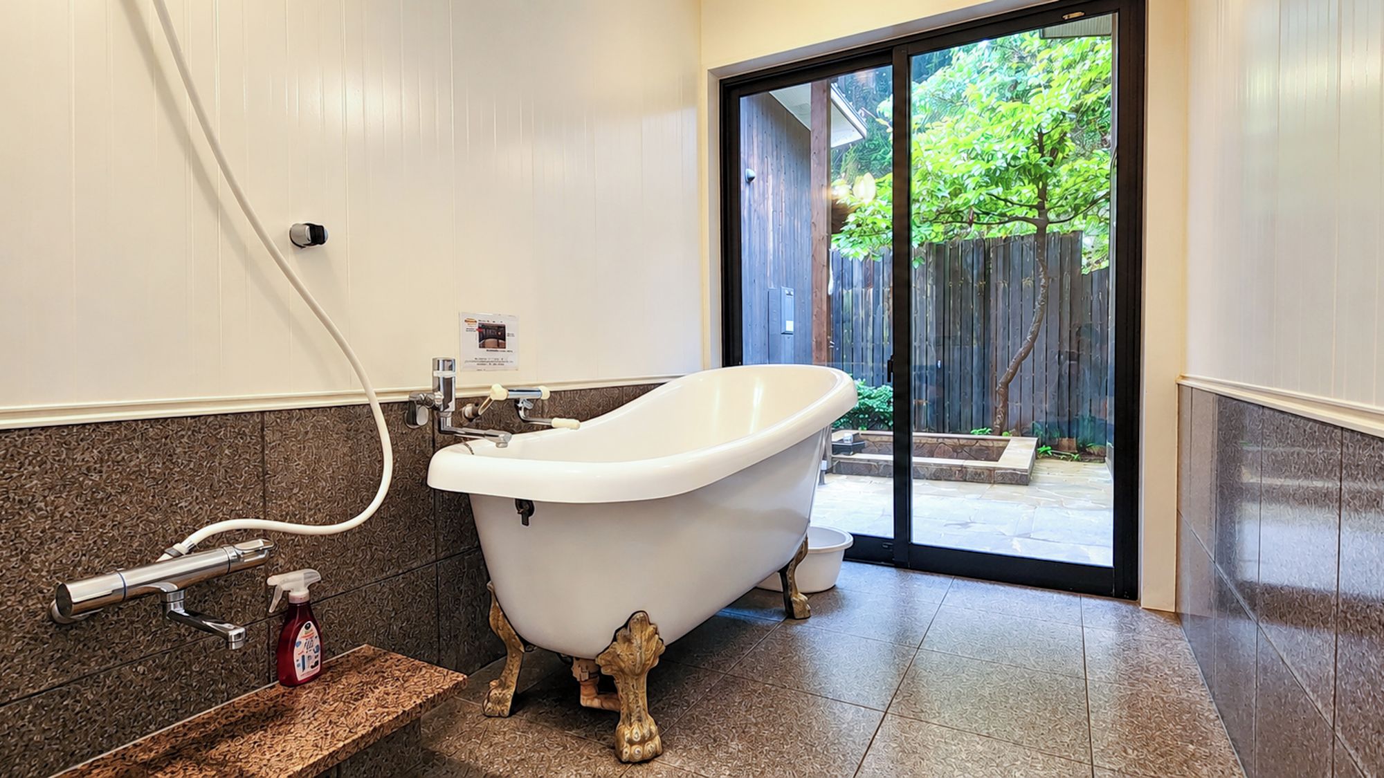 A bathroom with a freestanding bathtub, a towel rack, and a bottle of hand soap on a countertop.