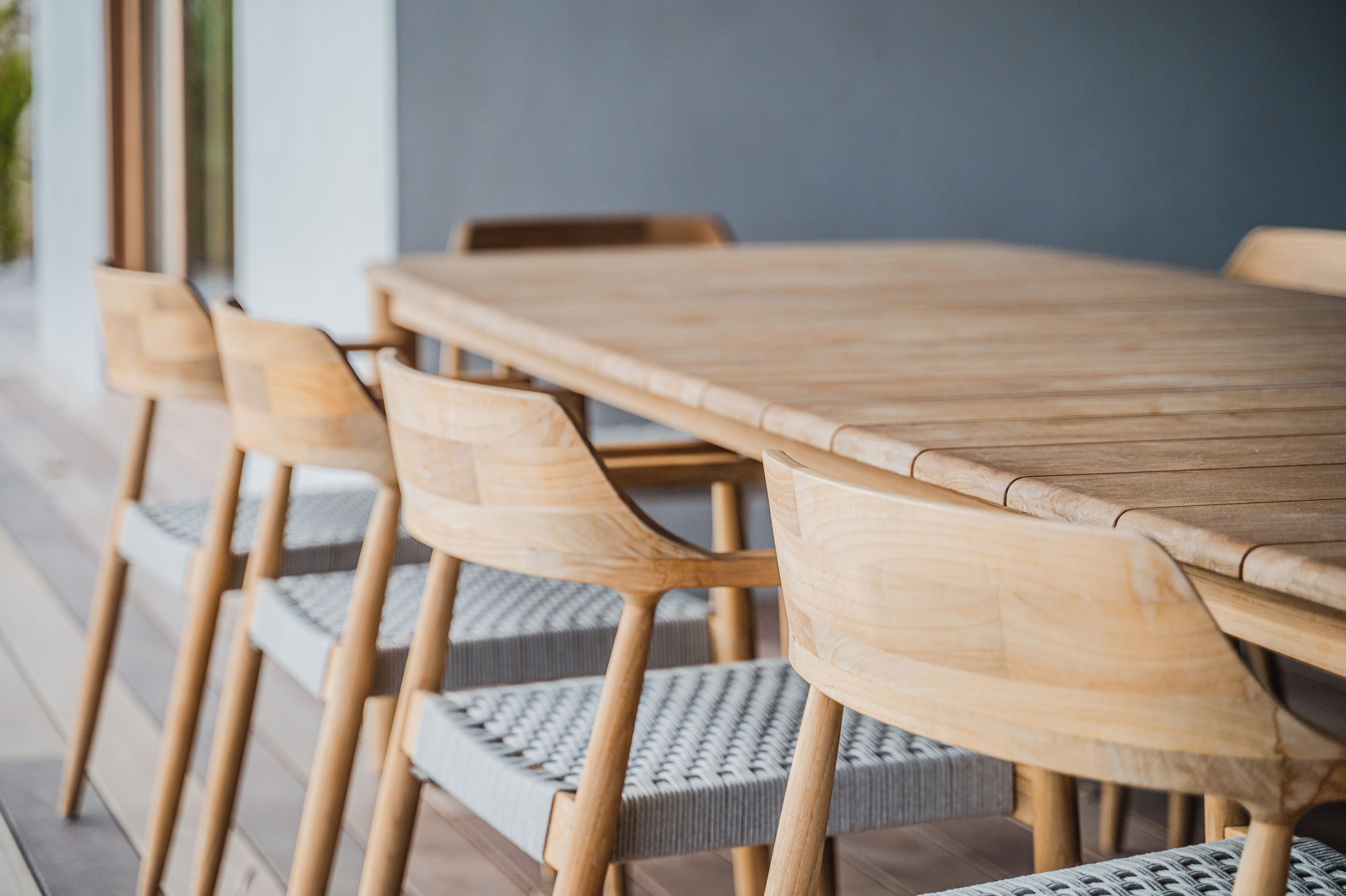 Een houten eettafel met zes stoelen, elk voorzien van een rieten zitting.