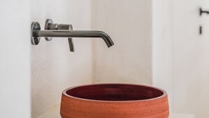 A bathroom with a round, terracotta-colored sink mounted on a white pedestal. - Kas Amare (Kralendijk)