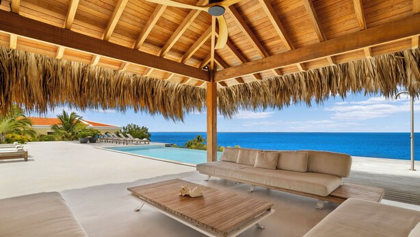 A covered outdoor area with a pool, a sofa, and a wooden table. - Kas Amare (Kralendijk)