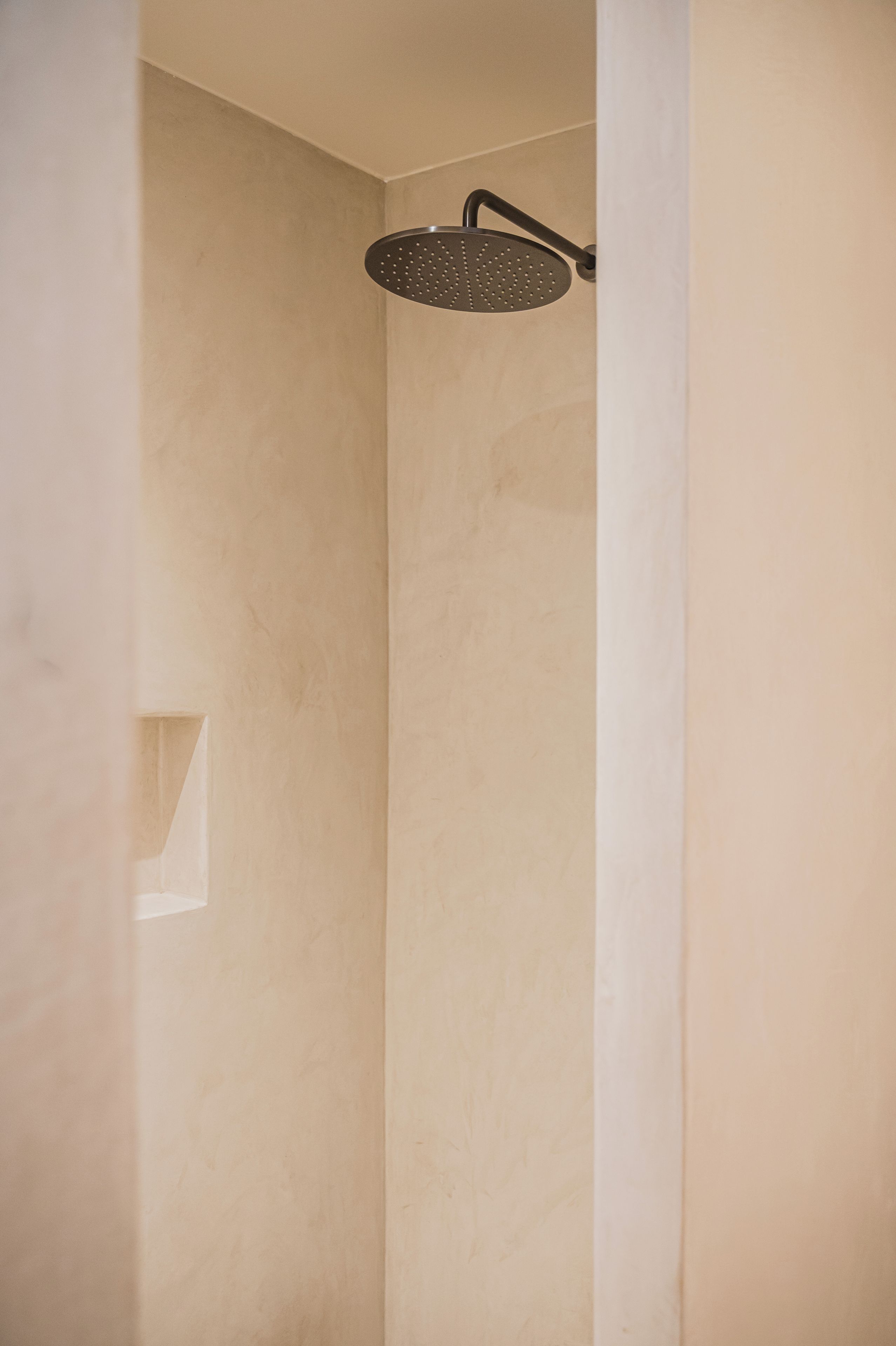 A shower with a round head and a wall-mounted handle.