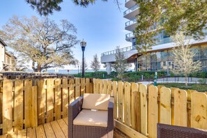 A wooden deck with wicker furniture, overlooking a modern building and a body of water. -  Tampa vacation rental, located just one block from Bayshore Boulevard! (Tampa)
