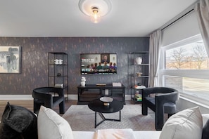 A modern living room with a black sofa, a coffee table, and a TV mounted on the wall.