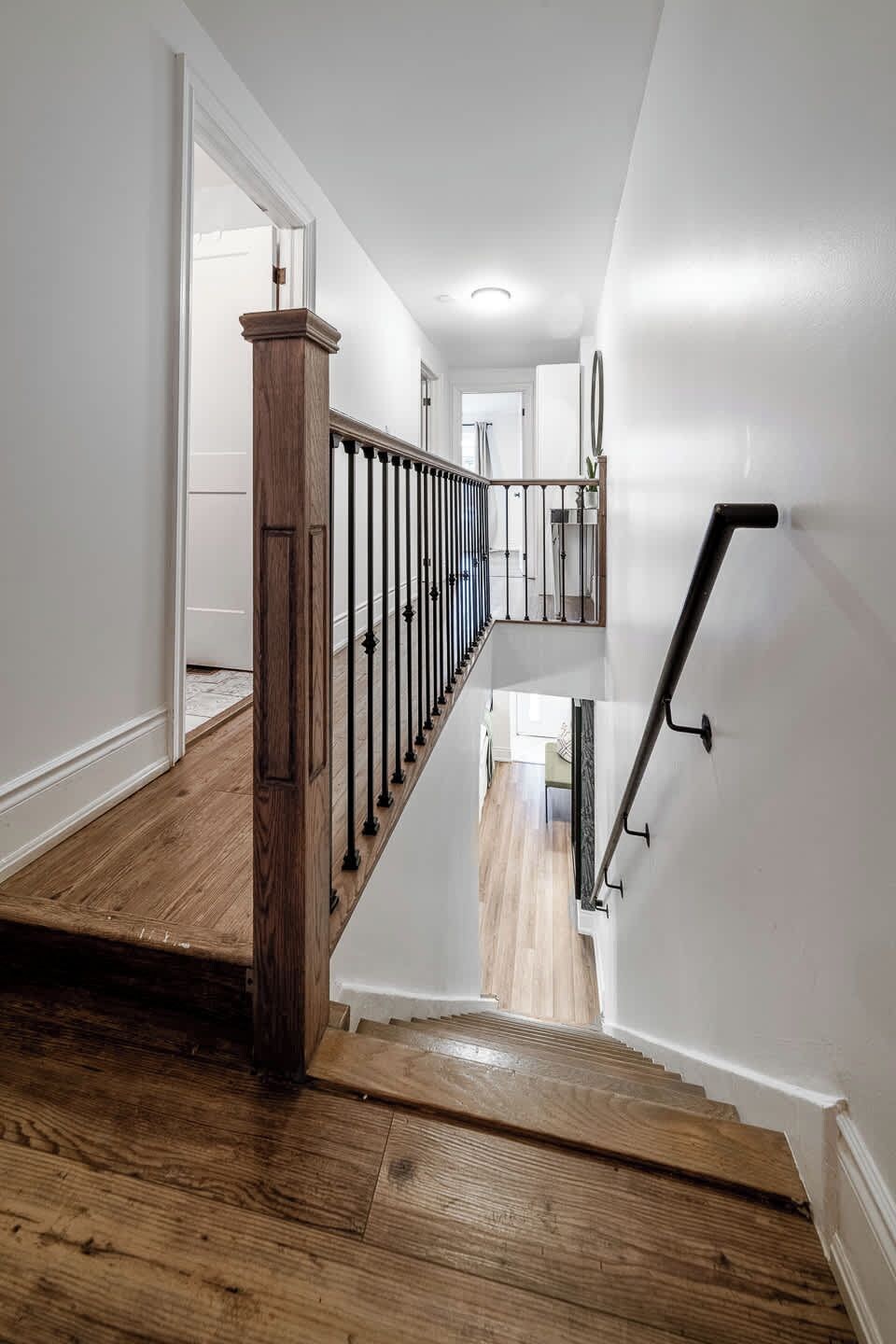 A staircase with a wooden handrail and metal balusters, leading to an upper floor.