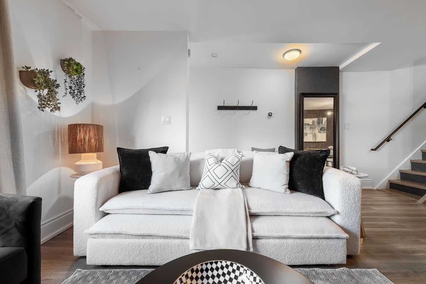 Ein modernes Wohnzimmer mit einer Couch, einer Lampe und einer Treppe.