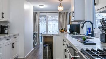 A modern kitchen with a built-in oven, a stainless steel range hood, and a window overlooking a balcony.