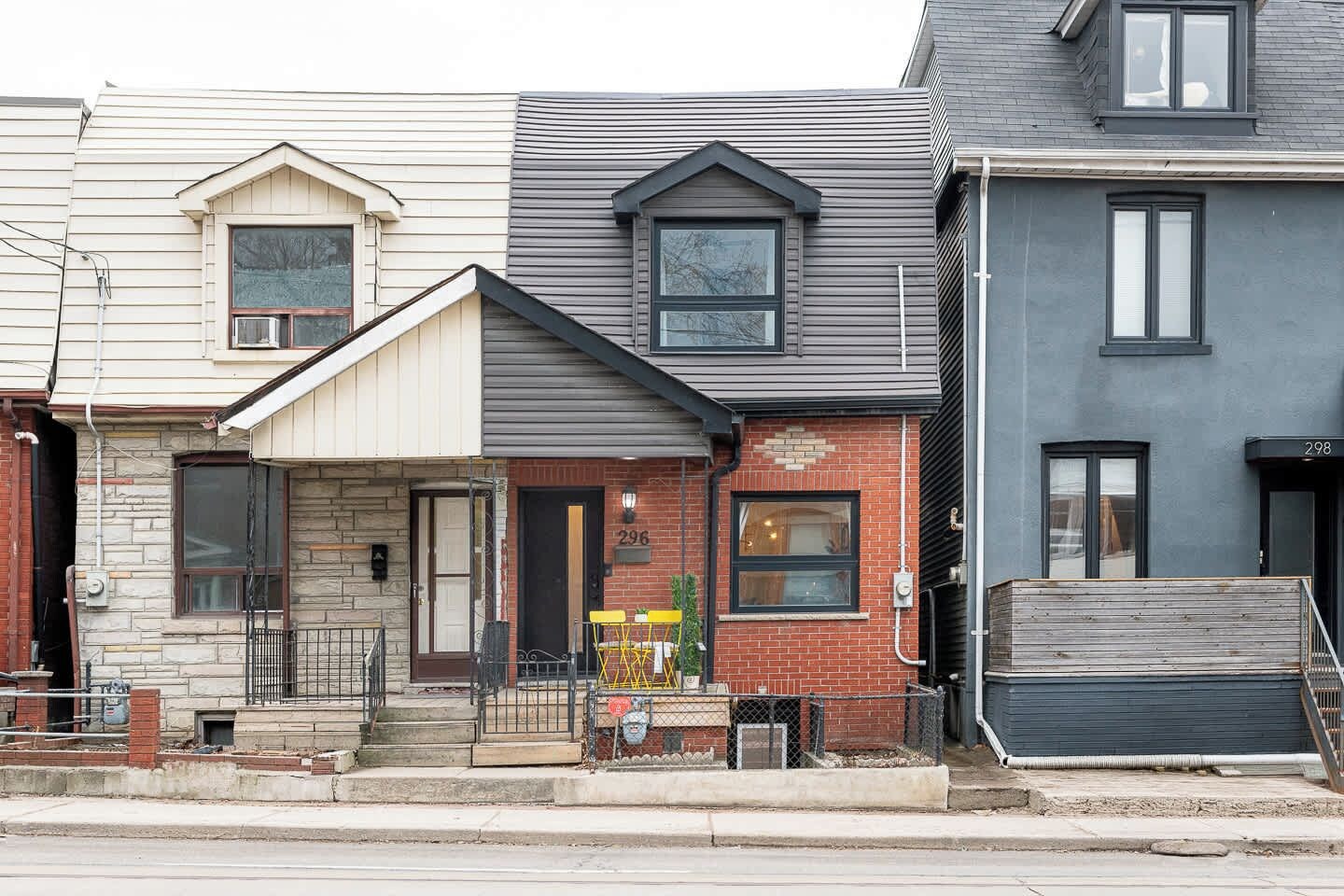 A row of residential buildings with distinct architectural styles, including a house with a visible front door and steps leading to the entrance.