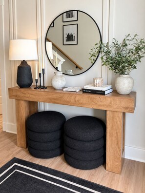 A wooden console table with a mirror, books, candles, and a potted plant. - Modern Charlotte Retreat - Sleeps 10 - Near UNCC & Uptown (Charlotte)