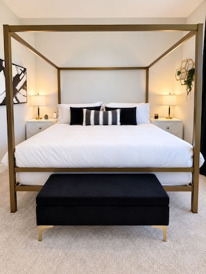 A four-poster bed with a black bench in front, white bedding, and two bedside tables with lamps. - Modern Charlotte Retreat - Sleeps 10 - Near UNCC & Uptown (Charlotte)