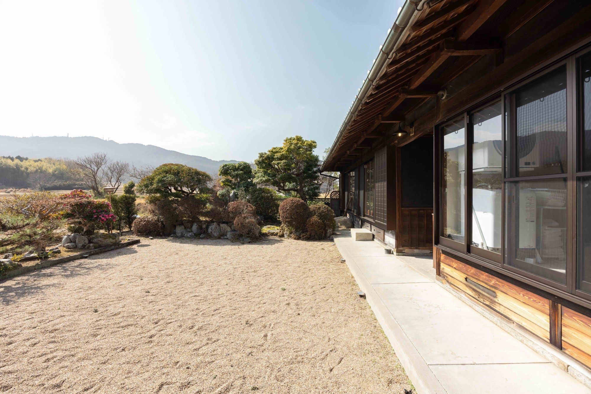 A traditional Japanese-style building with a gravel courtyard and a view of distant mountains.
