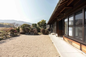 A traditional Japanese-style building with a gravel courtyard and a view of distant mountains.