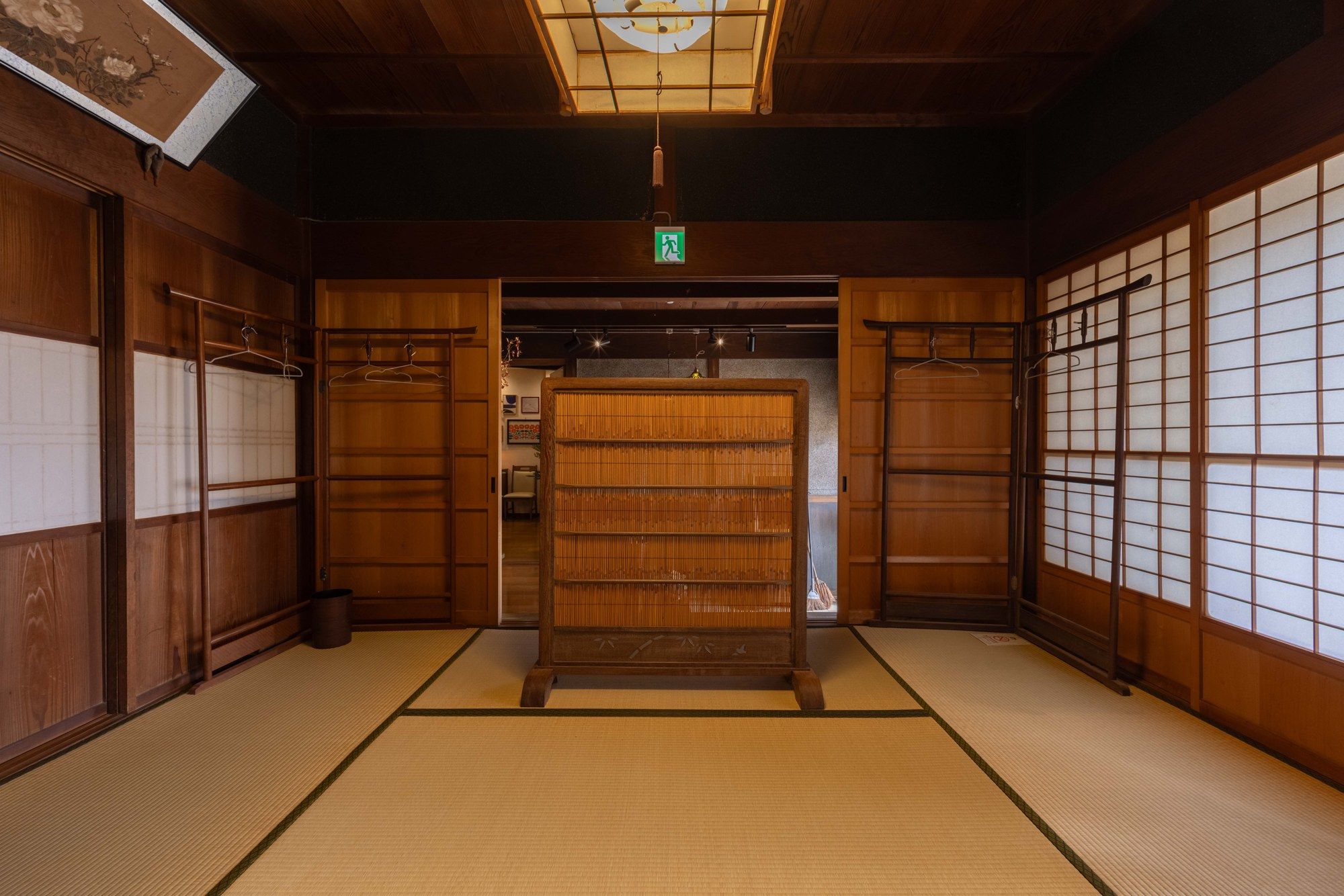 A traditional Japanese room with tatami flooring, sliding doors, and a hanging light fixture.