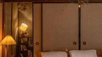 A bedroom with a bed, a nightstand, a lamp, and a bookshelf.