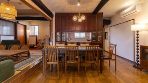Uma sala de jantar com mesa e cadeiras de madeira, um lustre e uma cozinha com armários de madeira e uma janela.