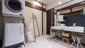 Casa de banho moderna com máquina de lavar roupa, duas pias e um espelho.