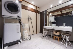 Moderni kylpyhuone, jossa on pesukone, kaksi pesuallasta ja peili.