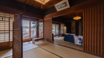 Una habitación japonesa tradicional con suelo de tatami, puertas correderas y vistas a un jardín.