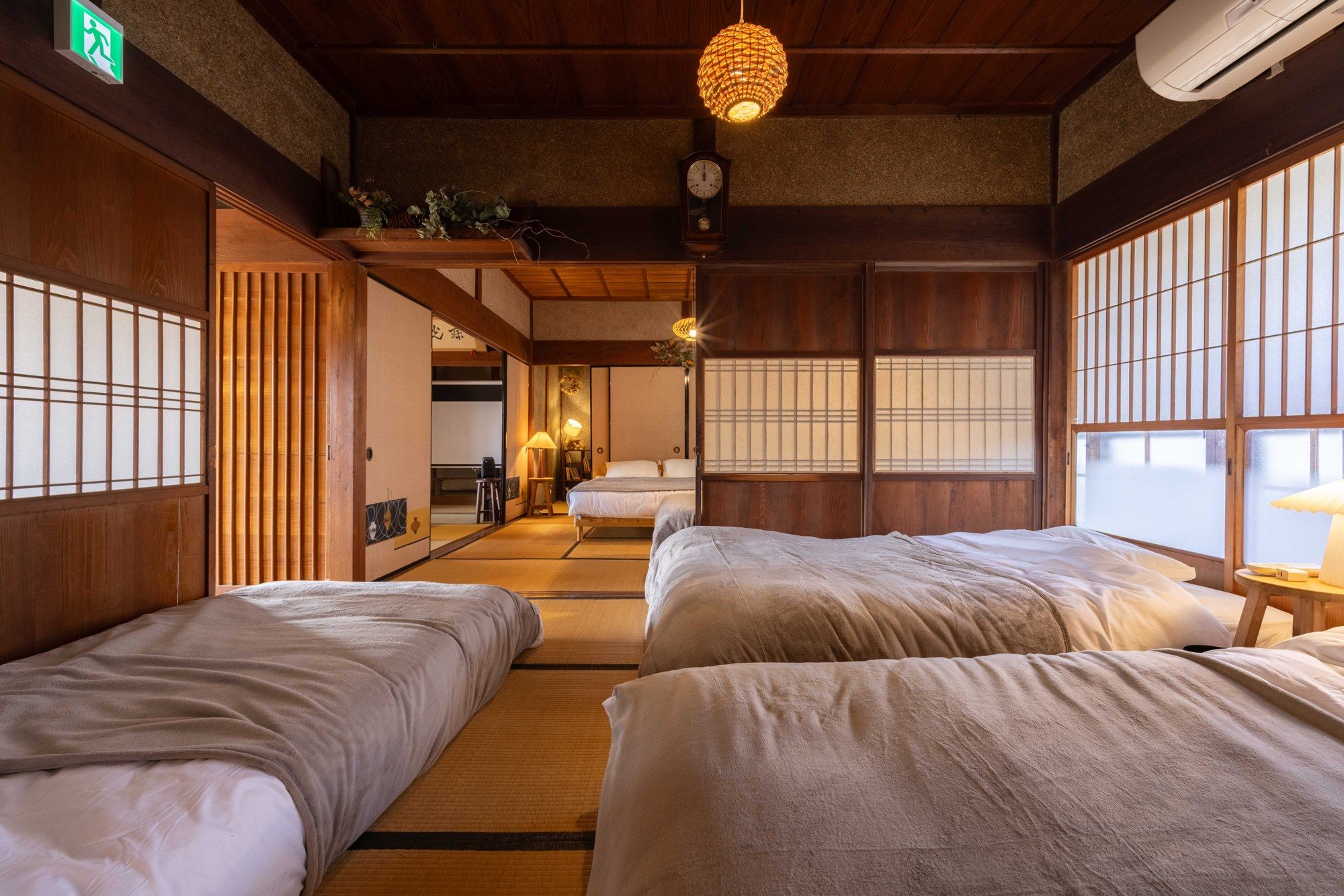 A traditional Japanese-style room with tatami flooring, shoji screens, and a hanging light fixture.