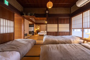 A traditional Japanese-style room with tatami flooring, shoji screens, and a hanging light fixture.