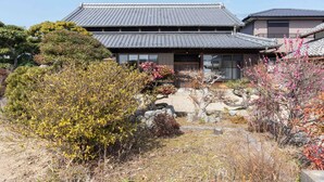 Um edifício japonês tradicional com telhado telhado e um caminho de pedra que leva à entrada.