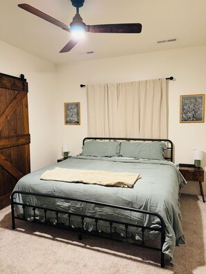 Un dormitorio con una cama, ventilador de techo, mesita de noche y dos lámparas de pared.