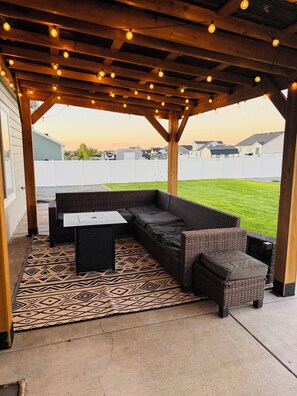 Eine Terrasse im Freien mit überdachter Sitzgelegenheit, einem gemusterten Teppich und Blick auf eine Wohngegend.
