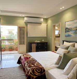 A bedroom with a bed, bedside tables, a dresser, an air conditioning unit, and a window. - Ramses Abu Simbel Hotel (Aswan Governorate)