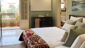 Ein Schlafzimmer mit einem Bett, Nachttischen, einem Schminktisch und einer Klimaanlage sowie einem Fenster.
