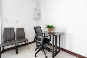 A conference room with two grey chairs, a black office chair, a glass table, a potted plant, and a white air conditioning unit on the wall. - Elyana Villa - 3-Bedroom Oasis in Rawai (Tambon Rawai)