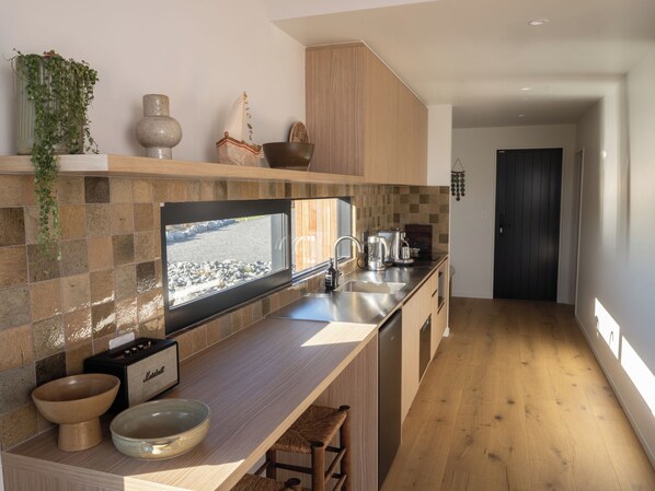 A modern kitchen with a large window, a built-in stove, and a wooden countertop.