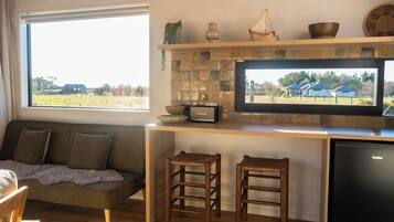 Una cocina con un ventanal amplio, un televisor de pantalla plana, un banco de madera y un lavavajillas.
