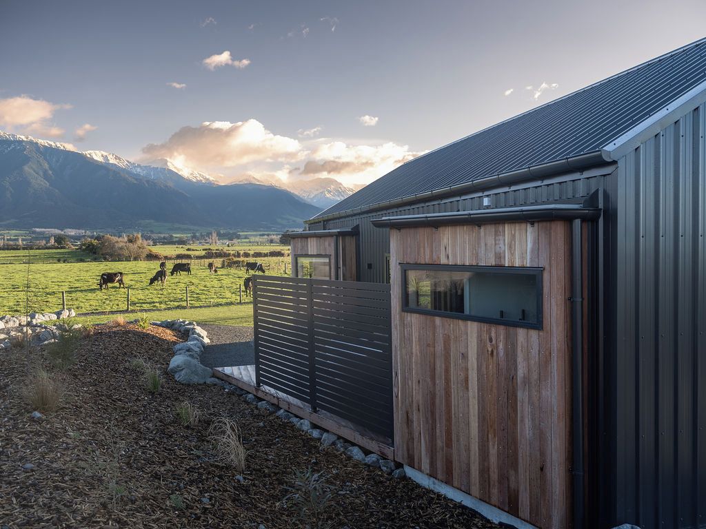 A rural property with a barn, a fenced pasture with grazing animals, and mountains in the background.