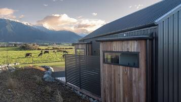 A rural property with a barn, a fenced pasture with grazing animals, and mountains in the background.