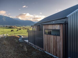 A rural property with a barn, a fenced pasture with grazing animals, and mountains in the background.
