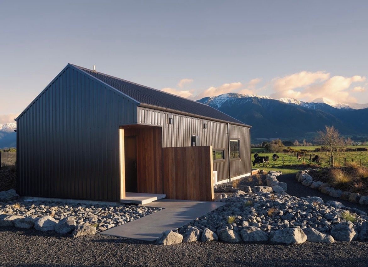 A modern building with a sloped roof, a wooden door, and a view of a mountainous landscape.