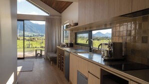 A modern kitchen with a view of a mountainous landscape. - Infrared sauna, outdoor bath, close to town and mountain bike trails (Kaikōura)