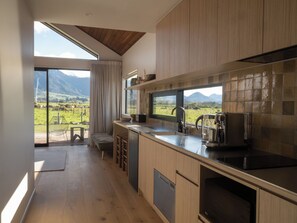 A modern kitchen with a view of a mountainous landscape. - Infrared sauna, outdoor bath, close to town and mountain bike trails (Kaikōura)