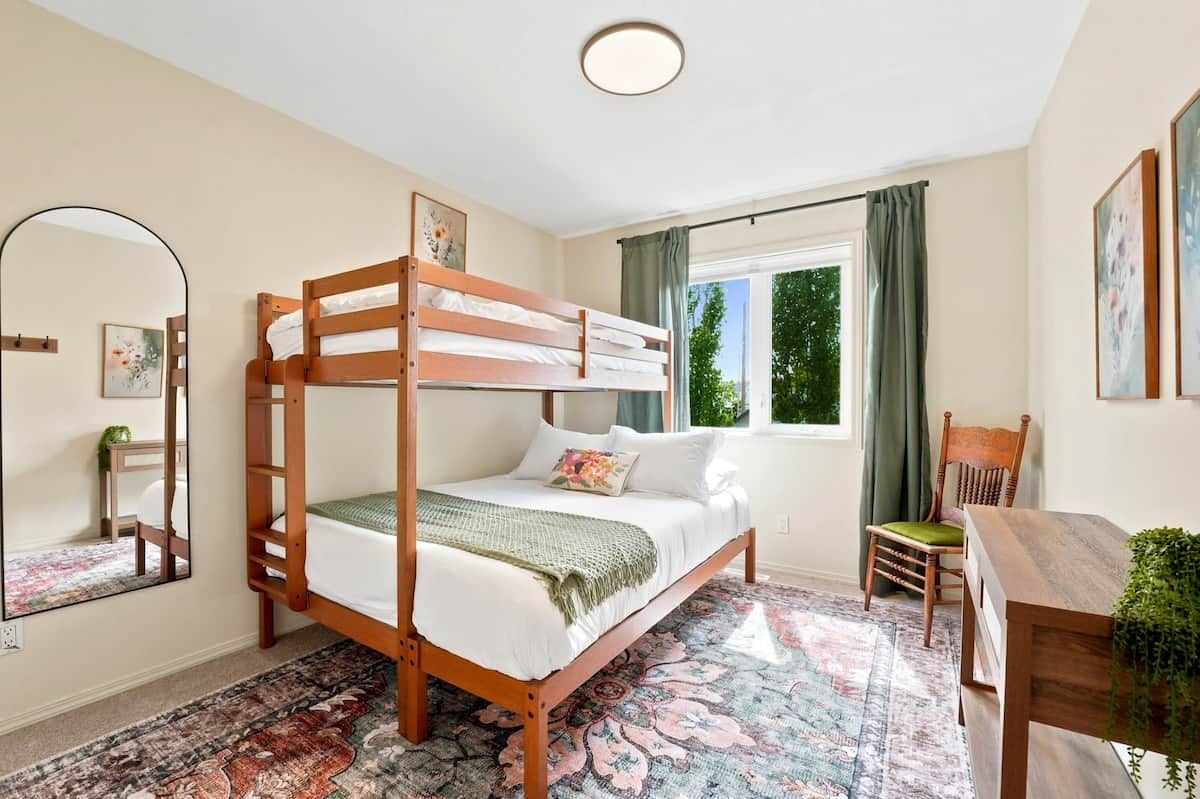 A bunk bed room with a window, a desk, and a chair.