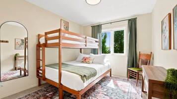 A bunk bed room with a window, a desk, and a chair.