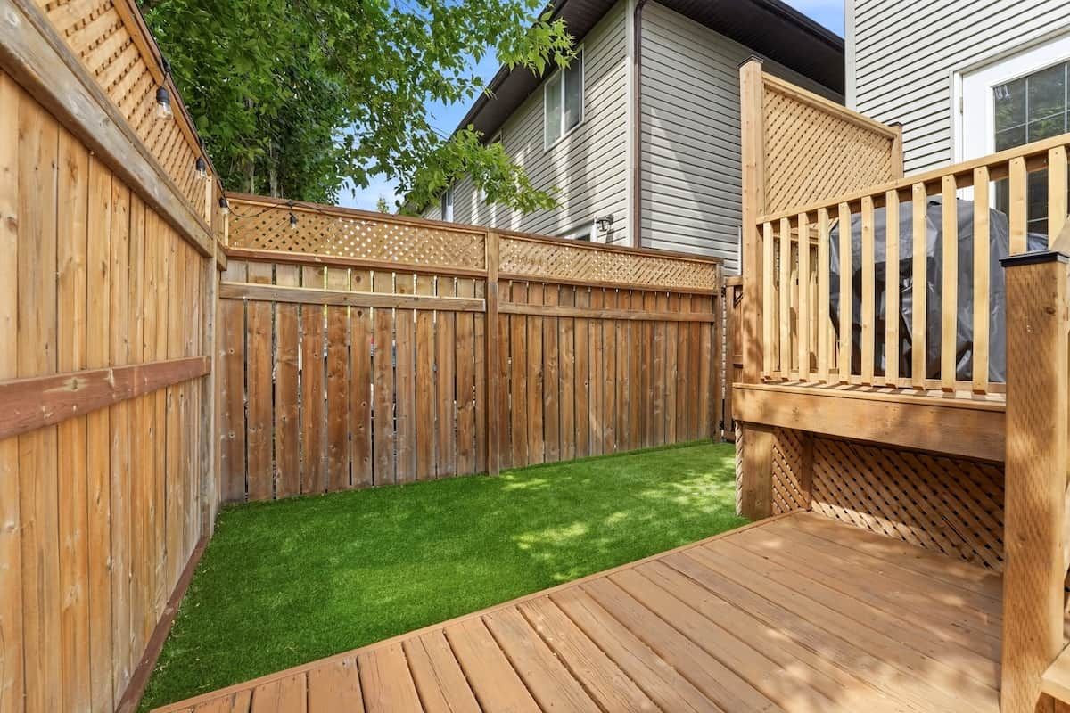 A wooden deck with a wooden fence and a small grassy area.