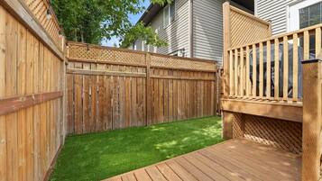 A wooden deck with a wooden fence and a small grassy area.