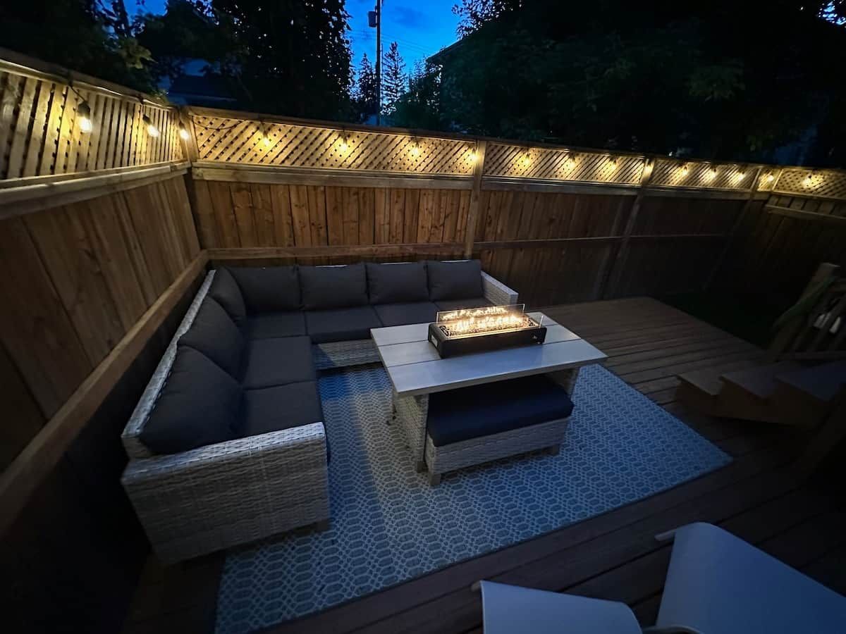 An outdoor seating area with a fire feature, cushioned seating, and a wooden deck.