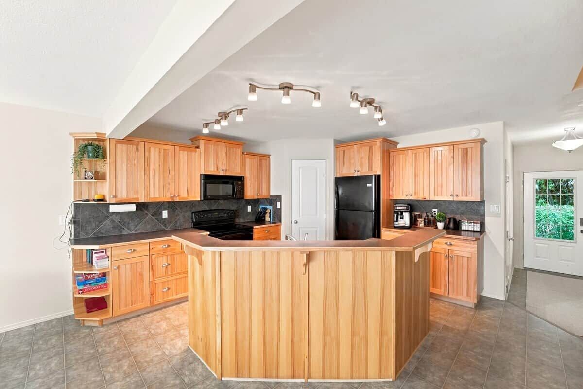A modern kitchen with wooden cabinets, a central island, and built-in appliances.