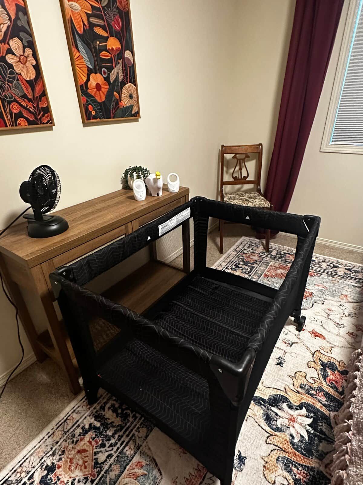 Ein Zimmer mit einem Holztisch, einem schwarzen Stuhl, einem Ventilator und einem dekorativen Teppich.